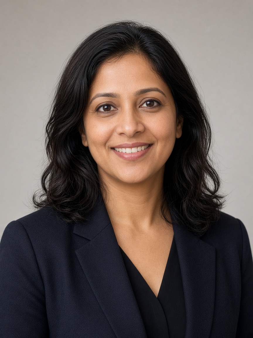 Maya Iyer smiling, in a dark blazer