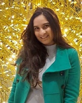 Shreya Kothari smiling, in a green coat